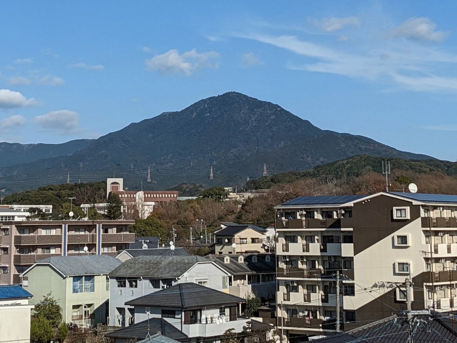 青空の下、家々の向こうにそびえる宝満山